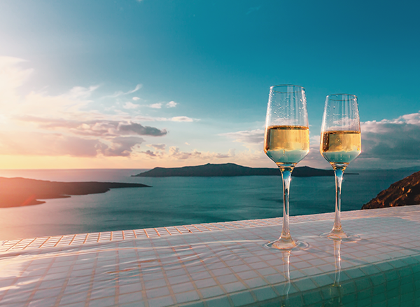 Travel services - wine glasses on edge of pool at sunset